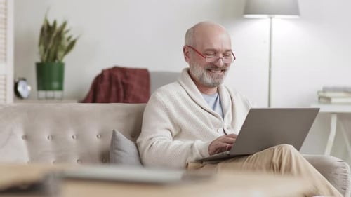 Senior Man Smiling Using Laptop at Home
