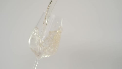 Pouring Transparent Liquid Into a Glass on White