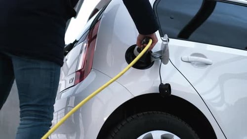 Close Up Man Hand Inserts Power Cable From Electric Car