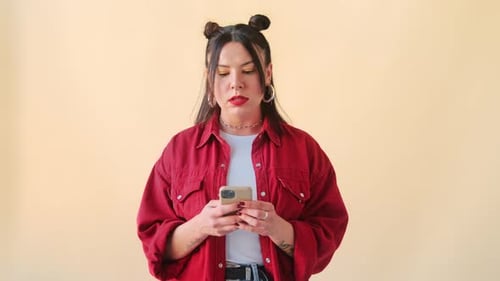 Stylish Woman Using Cellphone in Front of Backdrop