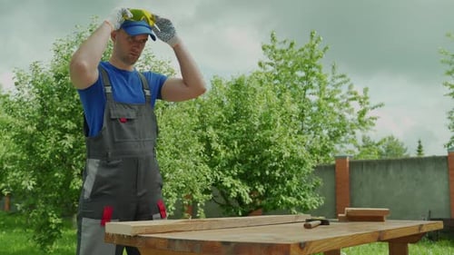 Man Putting on Gloves and Safety Glasses Outdoors