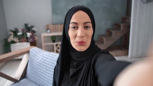 Woman in Headscarf Smiling and Talking Indoors