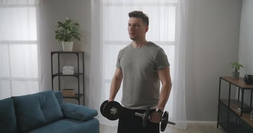 Man Lifting Dumbbells Exercising at Home