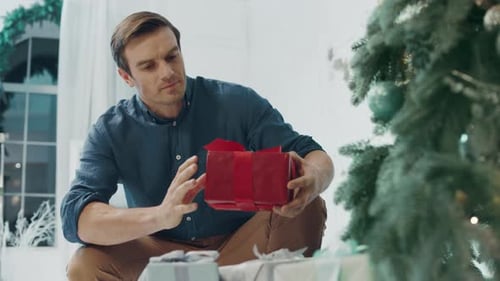 Man Placing a Christmas Gift Under the Tree