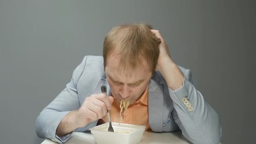 Man Eating Noodles from a Takeout Container