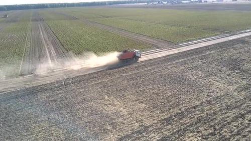 Flycam Follows Truck with Potatoes Driving Along Ground Road