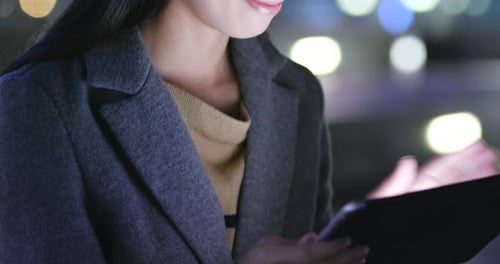 Woman Using Tablet at Night in the City