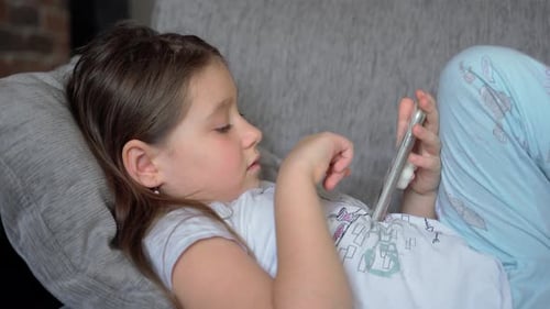 Girl Using Smartphone While Lying on Couch