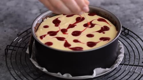 Unrecognizable Woman Preparing Cheesecake with Berry Sauce in the Kitchen. Close-up