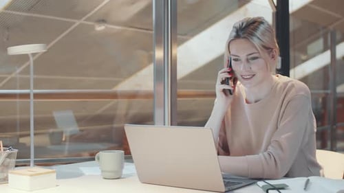 Woman Works at Laptop While Talking on Phone