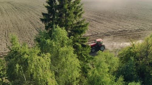 Red Tractor Tilling Field in Rural Landscape