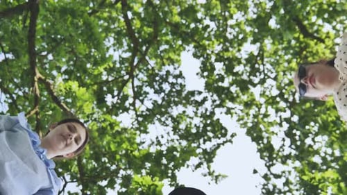 Girlfriends Girls Join Hands in the Summer Against the Background of Tree Branches