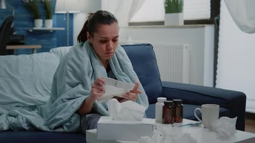 Woman Reading Medication Instructions on Sofa