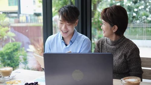 Colleagues Working Together on Laptop in Cafe