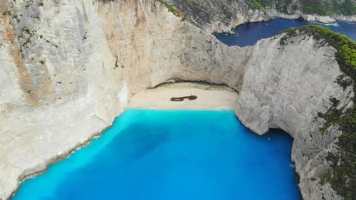 Eine Drohne fliegt an einem sonnigen Tag über den Schiffswrackstrand der Insel Zakynthos zurück