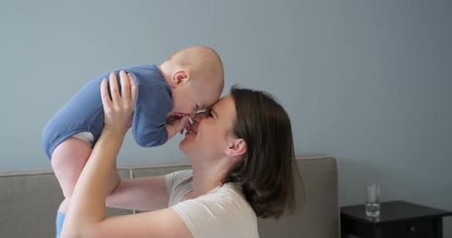 Mother Lifts and Kisses Adorable Baby at Home