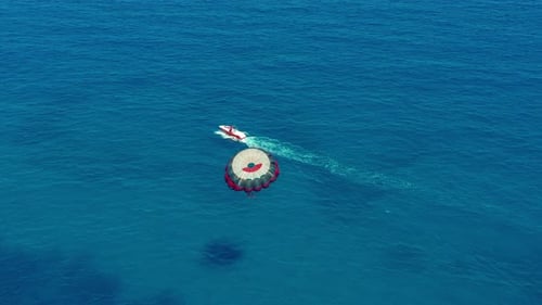 Aerial View. Flying with Parachute Behind a Boat. Extreme Water Sport in the Sea. Parasailing.