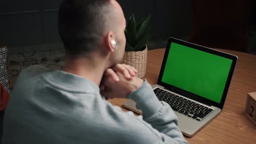 Closeup Back View Shot of Young Man Having a Video Call on the Laptop with Green Screen in the Home