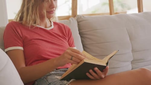 Woman Reading a Book on a Light Gray Couch