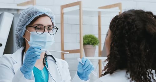 Arzt mit Schutzmaske entnimmt PCR-Testprobe von einer schwarzen Frau mit Coronavirus-Symptomen