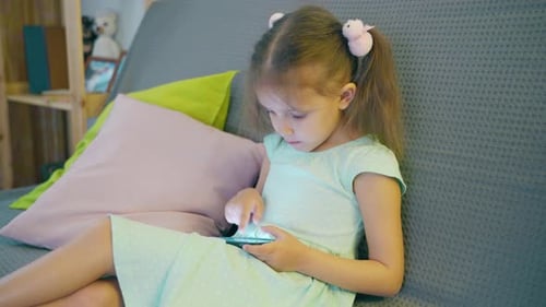 Young Girl on Sofa Using Smartphone