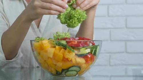 Adding Lettuce to Fresh Vegetable Salad Bowl