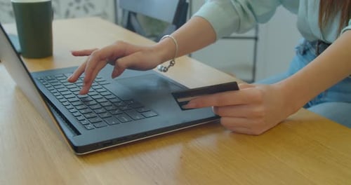 Woman Types on Laptop Holding Credit Card