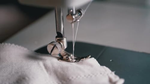 Close-up of Sewing Machine Needle with Thread Pierces Fabric in Slow Motion