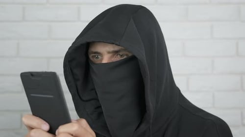 Hooded Figure Using Smartphone
