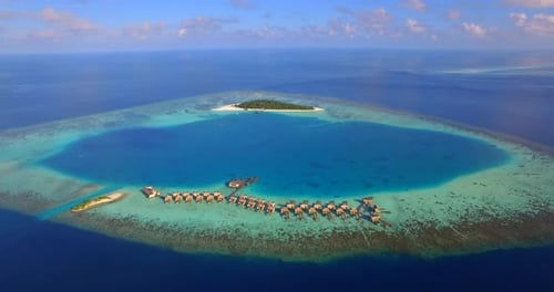 Vista aérea de drone da pitoresca ilha tropical e hotel resort com bangalôs sobre a água nas Maldivas.