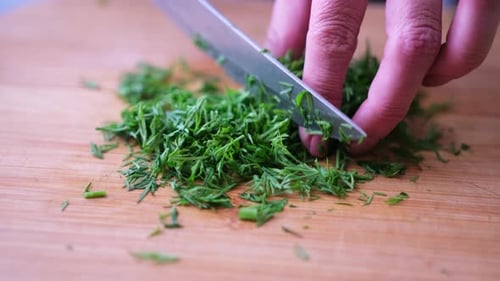 Fresh Dill Being Chopped on Wood Cutting Board