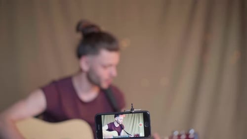 Man Playing Acoustic Guitar While Recording Video