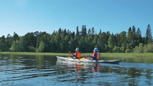 Man and Woman in Vests Sail Kayak Along Tranquil River
