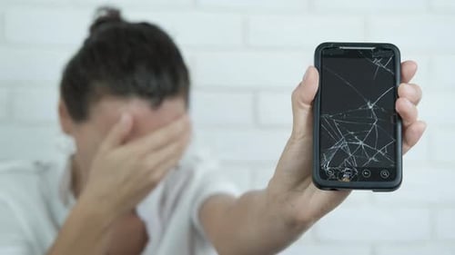 Woman Holding Broken Smartphone Displaying Cracked Screen
