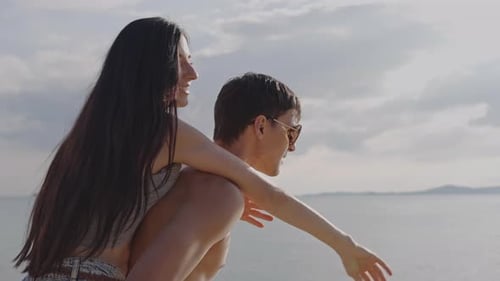 Woman piggyback ride on boyfriend walking on the beach