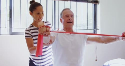 Senior Man Exercising with Assistance of Young Adult