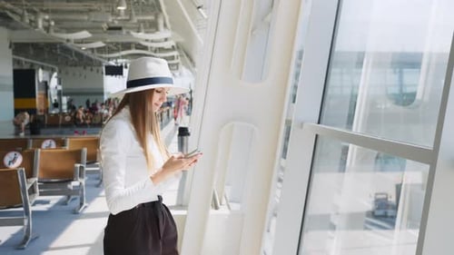 Girl Uses Smartphone in the Airport Lounge