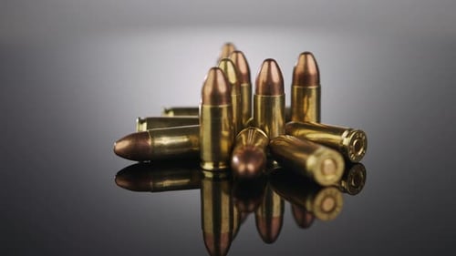 Waffenkontrolle. Munition aus 9-mm-Kugeln, die sich auf einer reflektierenden Oberfläche
drehen
