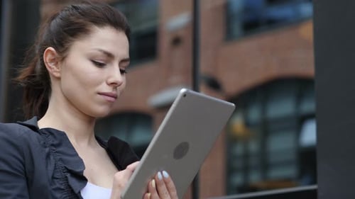 Woman Uses Tablet in Front of Brick Building