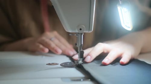 Stitching on sewing machine. Tailor sews on sewing machine. Close-up of woman's hand