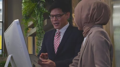 Entrepreneur talking with employee and looking desktop computer together at office.
