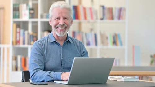 Man with Gray Hair Smiles Using Laptop