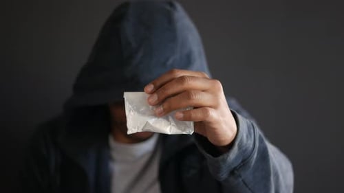 Drug Addiction Concept with Hand Holding Heroine Packet on Black Backgrund