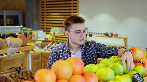 Shopper Carefully Checking Citrus Fruit in Grocery