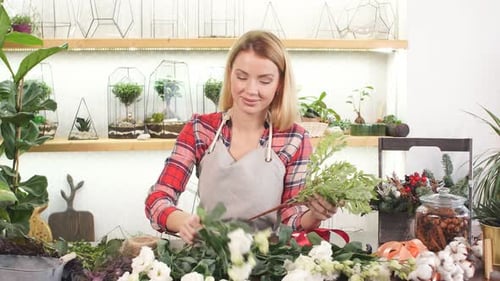 Woman Arranging a Bouquet of Flowers at a Table