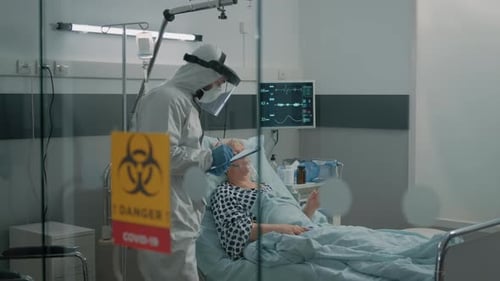 Doctor Examining Patient in Hospital Room with PPE
