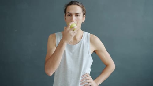 Man Eating Green Apple in Studio Setting