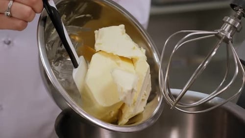 Nahaufnahme eines Chefs, der Butter in die Schüssel einer Küchenmaschine zum Schlagen gibt