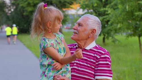 Little Granddaughter Child Embracing Kissing with Her Grandfather in Park Happy Family Relationship