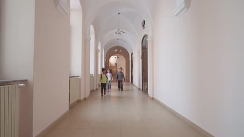 Children Walking Down School Hallway with Backpacks